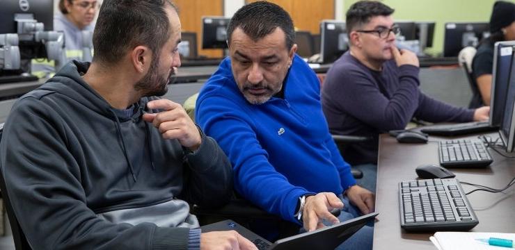 Two students discuss over computer